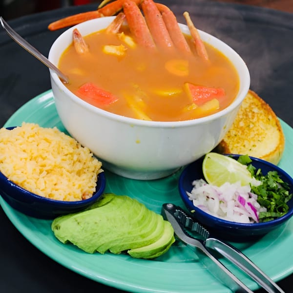 Vallarta Mexican Grill's seafood soup with crab legs, rice, avocado, and lime on a teal plate.